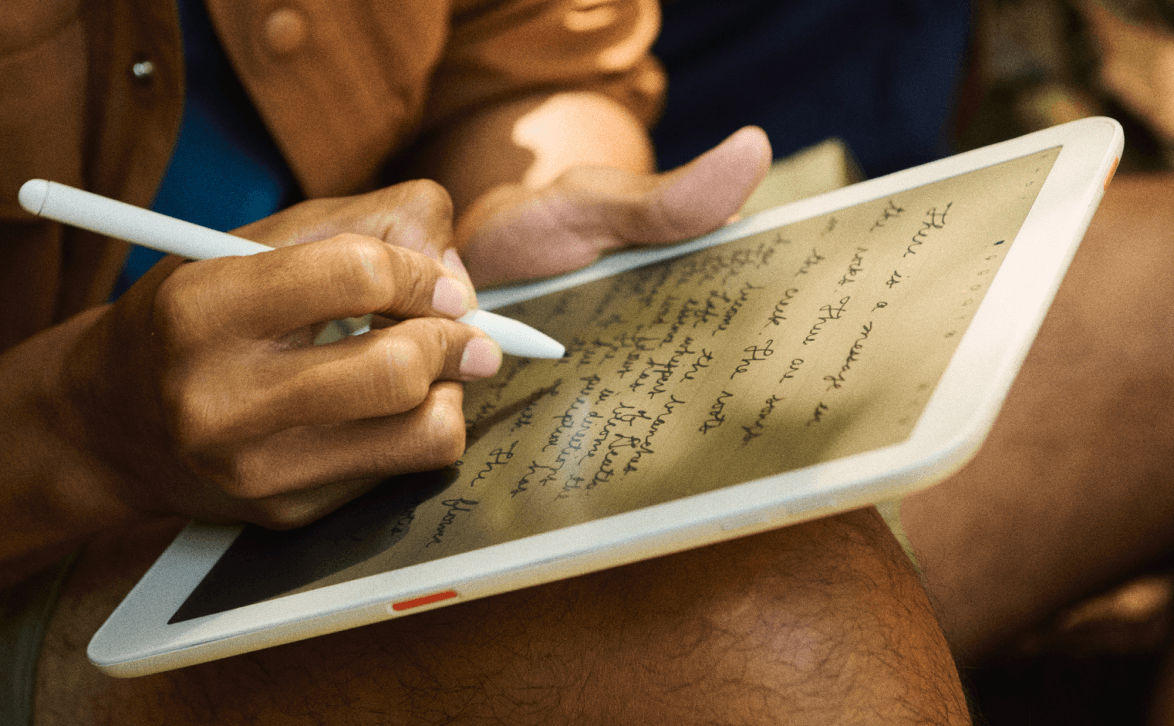 Person writing on a paper-like tablet surface